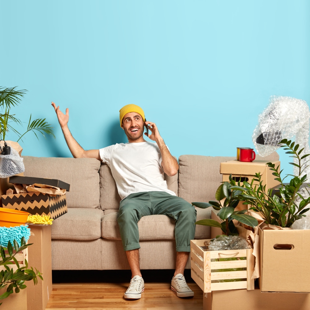 portrait-happy-man-has-phone-conversation-gestures-with-one-hand-tries-explain-route-his-new-apartment-wears-yellow-hat